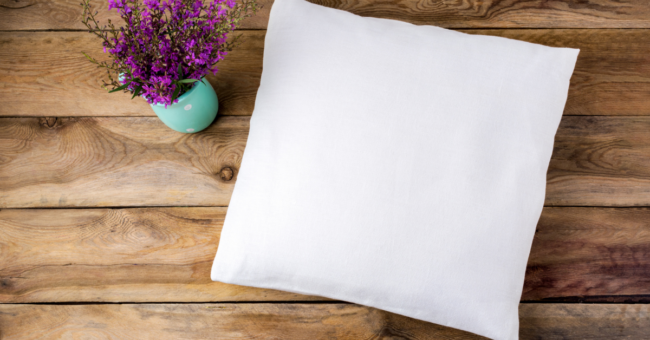 pillow rests next to a vase of flowers