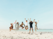 Group of friends jumping excitedly on a beach